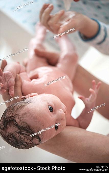 Mother is bathing Newborn baby girl taking a bath