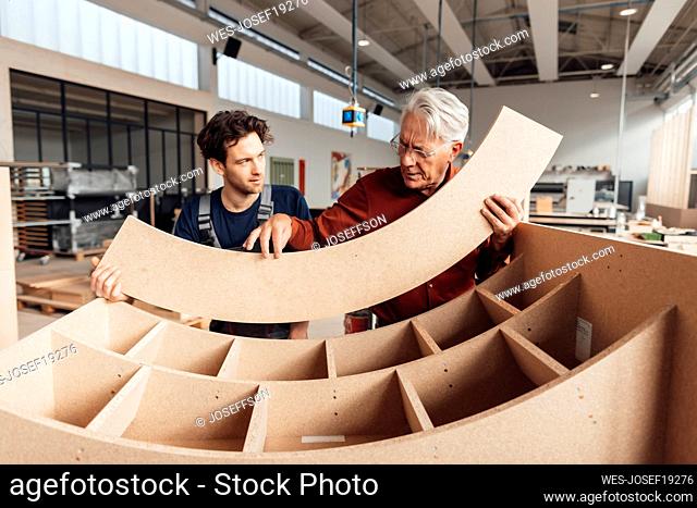 Businessman discussing over wood with carpenter in workshop