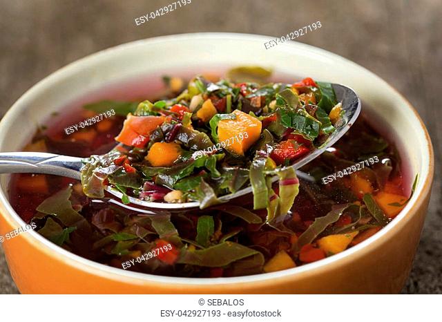 East Europe soup or red borscht in bowl with spoon over wood background