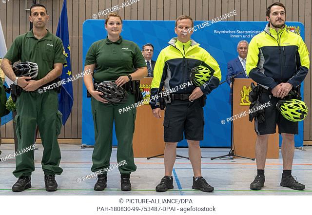 30 August 2018, Munich, Germany: After the conversion to new uniforms by Bavaria's police and judiciary, police and judiciary employees compare the new (r) and...