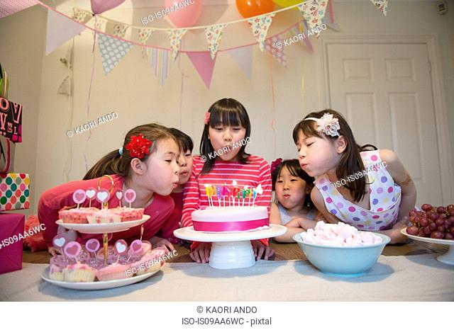 Girls blowing out birthday candles on cake