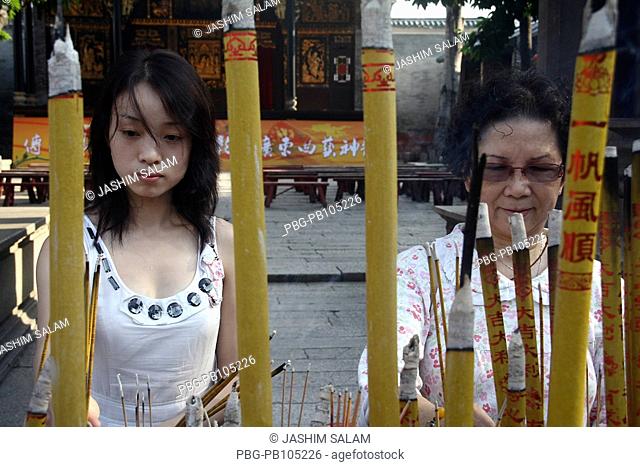 Chinese women igniting ritual fire in a temple Guangzhou, China September 2009