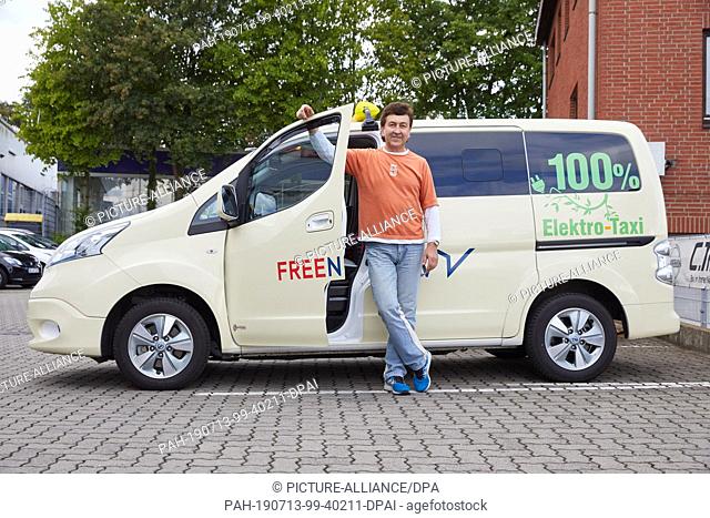 12 July 2019, Hamburg: Kostantin Khmelevskyy, taxi driver, stands next to his Nissan e-NV 200 Evalia with the inscription: ""100% electric taxi""