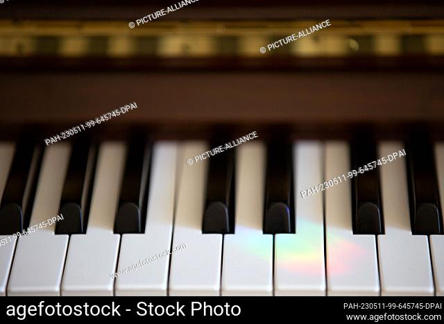 PRODUCTION - 30 April 2023, Berlin: On the keys of a piano in a living room, a light reflection in rainbow colors can be seen. Photo: Viola Lopes/dpa