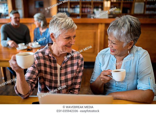 Smiling senior friends having cup of tea in restaurant