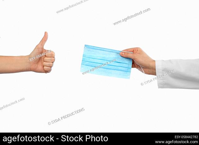 hand with mask and showing thumbs up