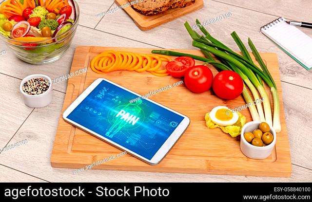 PAIN concept in tablet with fruits, top view