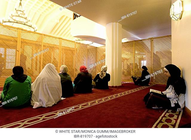 Women behind a screen during Friday prayers at the Mezquita Grande Mosque, sitting cross legged on a red carpet in the El Albayzín or Albaicín quarter of...
