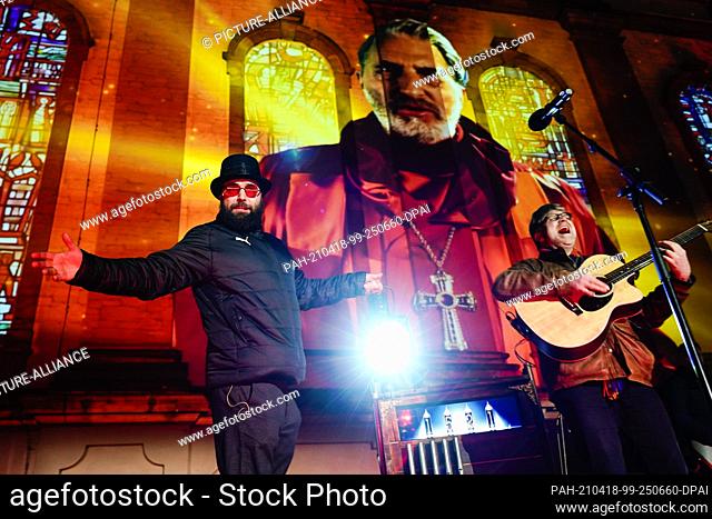 14 April 2021, Rhineland-Palatinate, Worms: Actor Isaak Dentler (l) stands on stage in front of a light projection at the Dreifaltigkeitskirche during a media...
