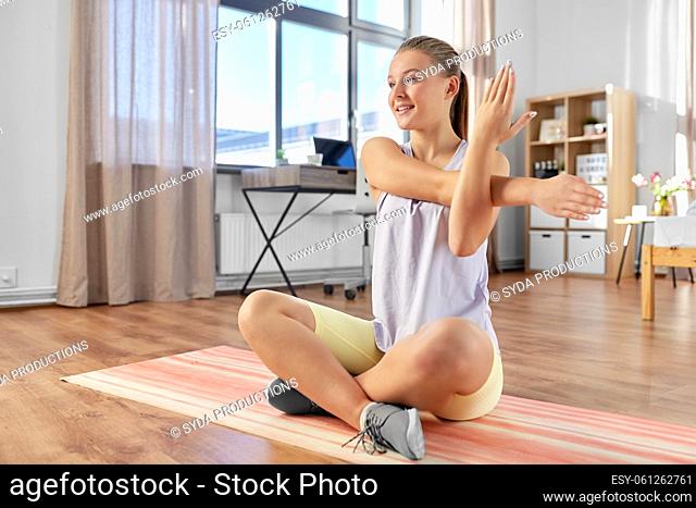 happy teenage girl exercising on yoga mat at home