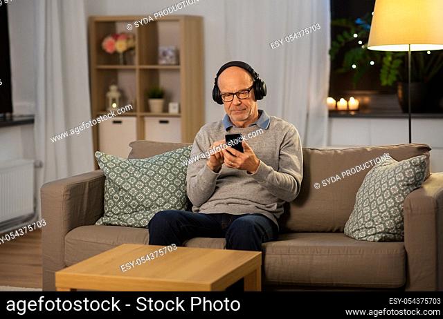 senior man with smartphone and headphones at home