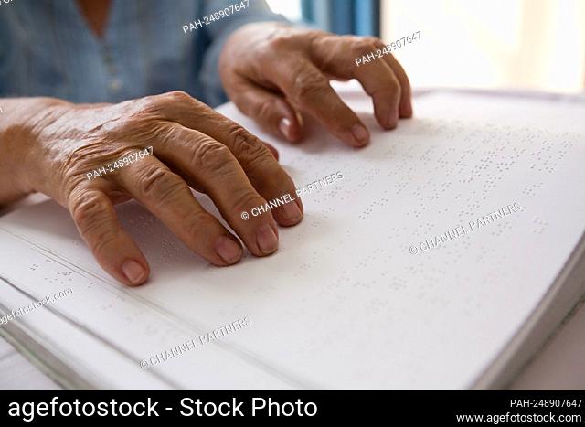 Cropped hands of senior woman reading braille in nursing home || Model approval available