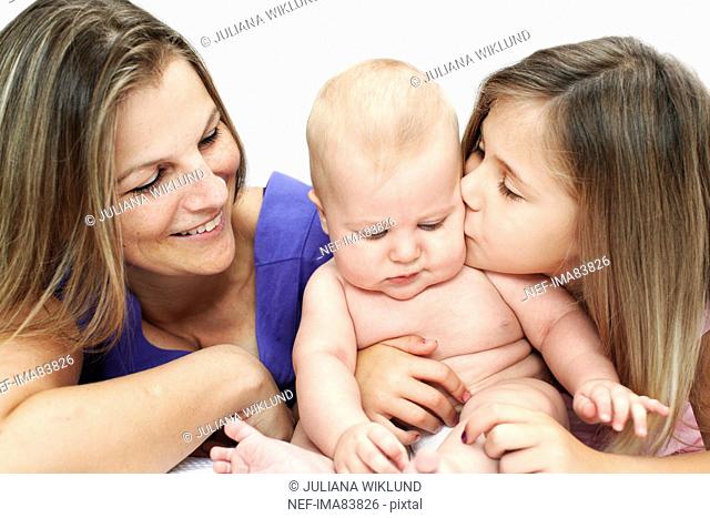 Mother looking at daughter kissing son