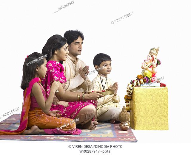 South Asian Indian family with father mother son and daughter sitting praying to lord Ganesha MR 698 , 699 , 700 , 701