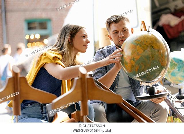 Belgium, Tongeren, young couple examining globe on an antique flea market