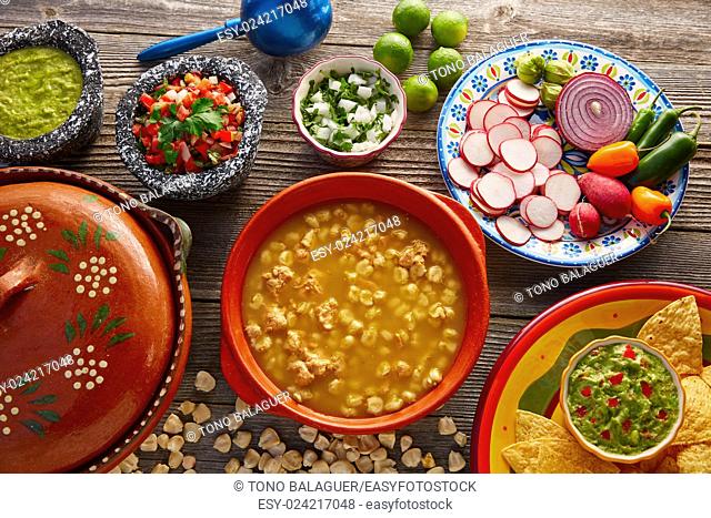 Green Pozole verde with blanco mote corn and ingredients on wooden table