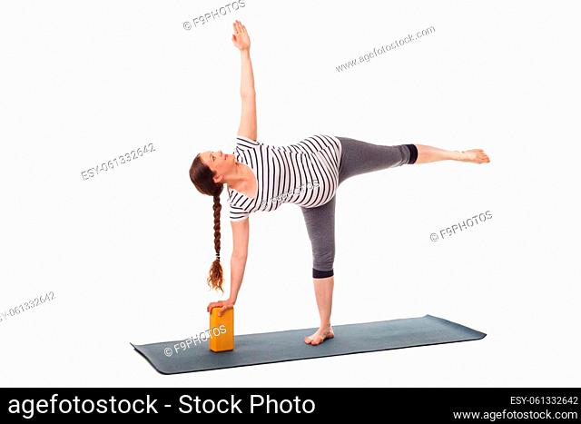 Pregnancy yoga exercise - pregnant woman doing asana virabhadrasana 3 - warrior pose with wooden block isolated on white background