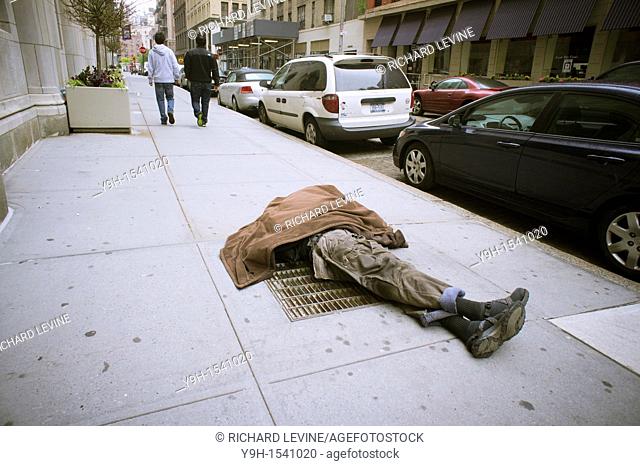 Homeless man sleeping on a vent in the sidewalk in Greenwich Village in New York With the deteriorating economy many worry about the return of crime and...