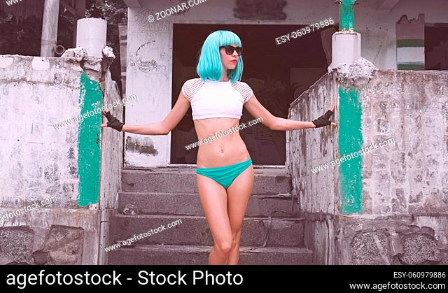 Sexy beautiful woman in modern futuristic style posing over abandoned building. Creative look of woman on the beach wearing bikini