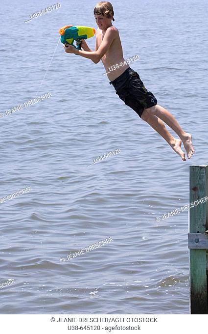 boy shooting water gun while jumping into the Albemarle Sound, 
North Carolina