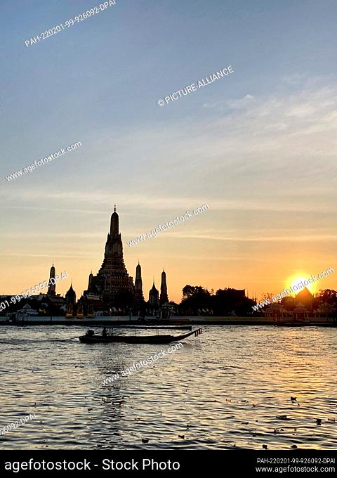 30 January 2022, Thailand, Bangkok: Wat Arun, the Temple of Dawn, seen at dusk from across the Chao Phraya River. Most tourist attractions are still deserted