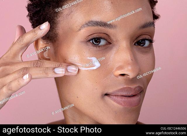 Studio portrait of woman applying cream on face