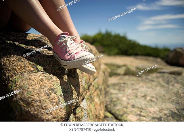 Detail of female wearing pink sneakers resting on rock  Acadia National Park, Bar Harbor ME