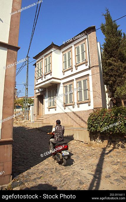 Motorcyclist in front of a traditional Ottoman-Greek house with bay window at the town center of Cunda or so-called Alibey Island-Alibey Adasi, Ayvalik
