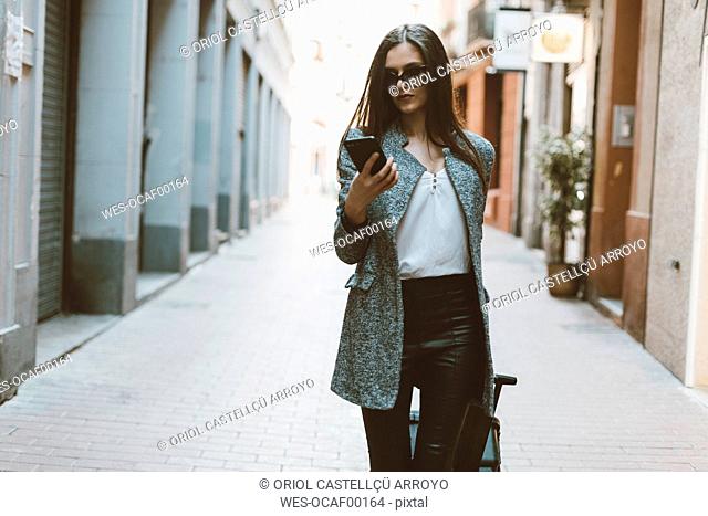 Young businesswoman in the city checking cell phone