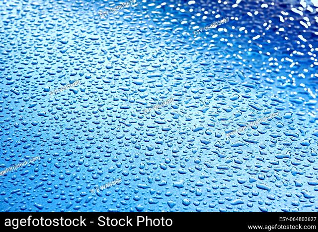 Drops of water on a gray-blue surface with slight sharpness and color gradient and slight bokeh on the right edge
