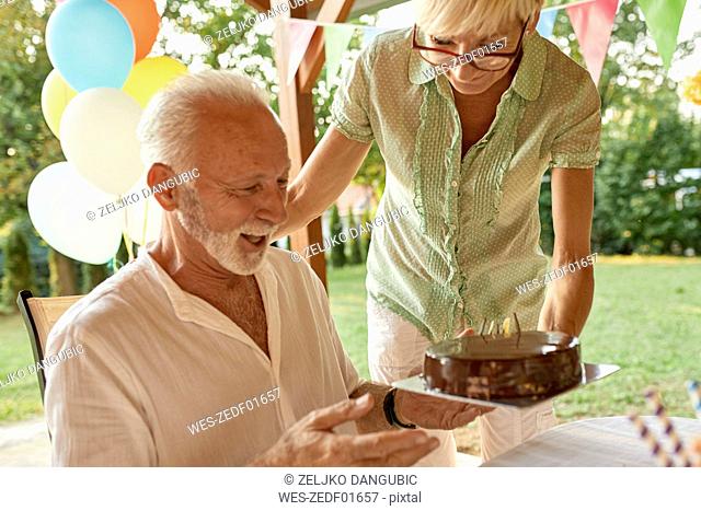 Woman handing over cake to happy husband on a garden party