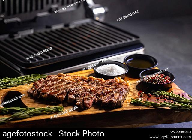 ribeye steak on wooden board with spices and electric grill