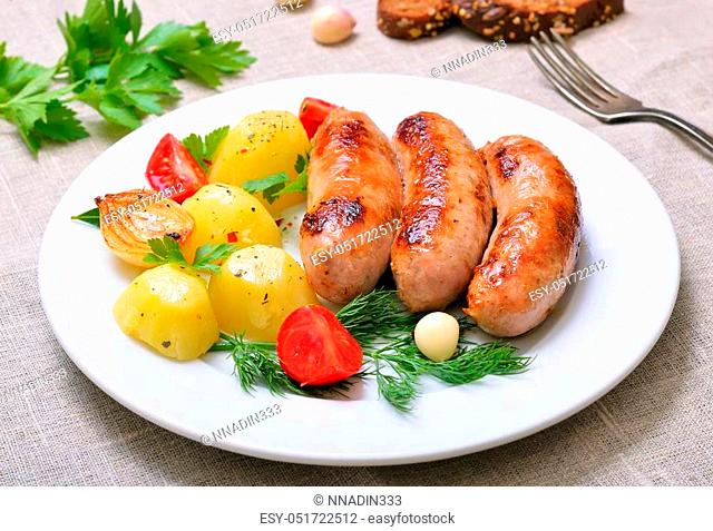 Barbecue sausages and boiled potatoes on white plate, close up