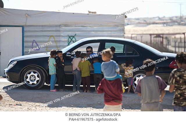 Refugees look at cars of the German delegation visiting the refugee camp in Zaatari, Jordan, 22 September 2015. The camp run by the United Nations High...