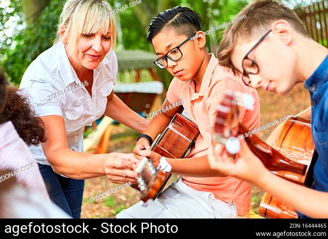 Lehrerin hilft Kindern im Gitarren Unterricht im Ferienlager vor der Talentshow