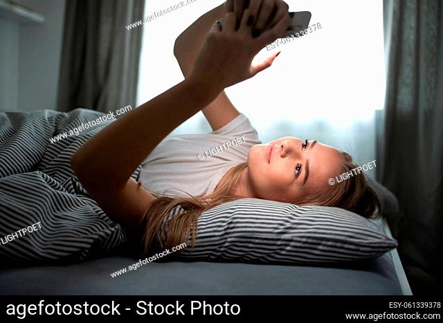 Pretty, young woman sleeping in her bed with her cell phone close to her. Smartphone in Bed Mobile/smartphone Addiction Concept