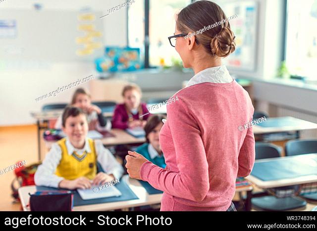 Teacher with her students in class at elementary school giving them an education