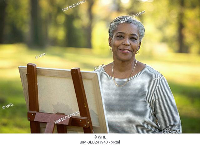 Portrait of Black woman painting on canvas in park