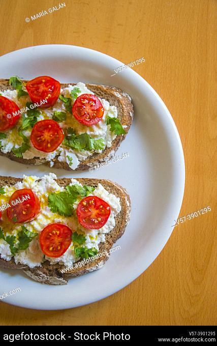 Cottage cheese with cherry tomatoes, olive oil and parsley on toast