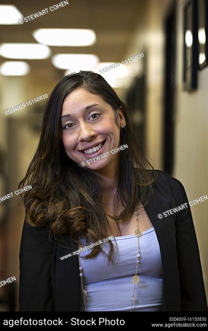 Portrait of young woman smiling in hallway of office building