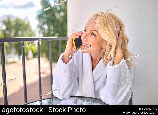 Phone call. A blonde woman in a white robe talking on the phone