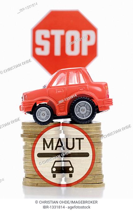 Miniature car on a stack of coins, symbolic image for car tolls