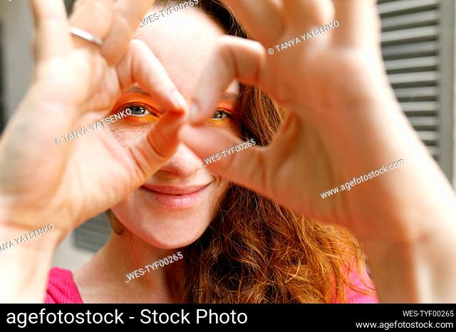 Smiling woman looking through binoculars made from fingers