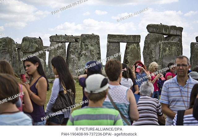 10 July 2013, Great Britain, Amesbury: Tourists visit Stonehenge, a Neolithic building. Photo: Frank Rumpenhorst/dpa. - Amesbury/Wiltshire/Great Britain