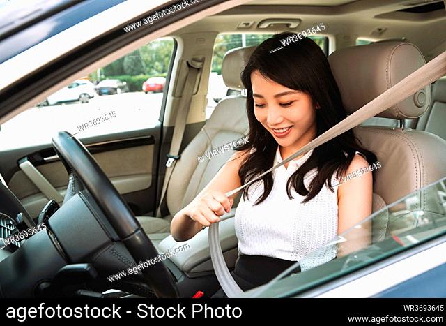 Driving young woman wearing a seatbelt