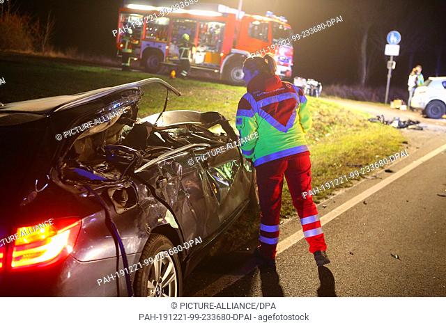 21 December 2019, Lower Saxony, Dransfeld: A member of the rescue service looks into a wrecked vehicle on the B3 near Dransfeld