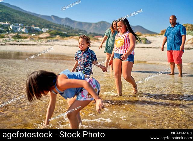 Family playing in water on sunny ocean beach