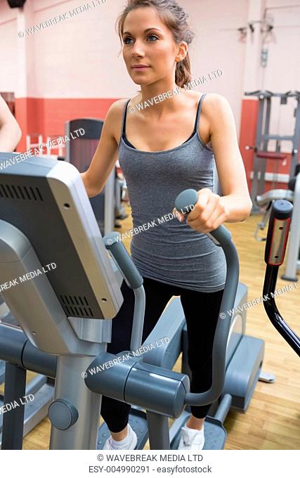 Brunette stepping on a step machine in gym