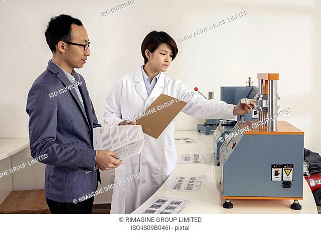 Technician explaining printing machine to manager in printing and packaging factory, China