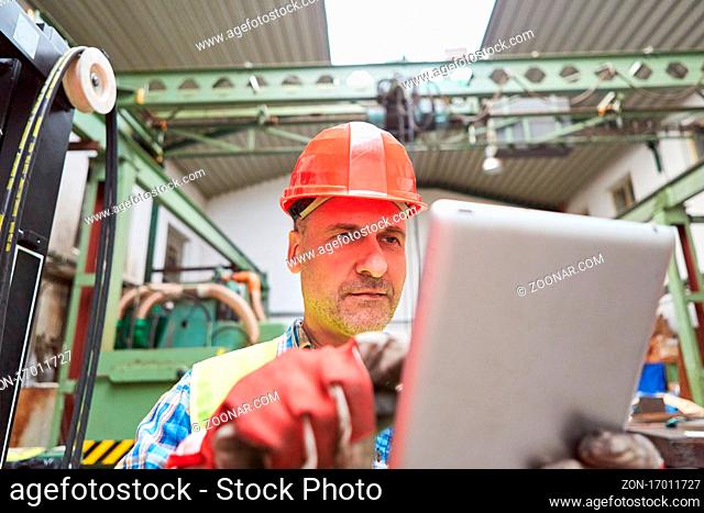 Handwerker am Tablet Computer bearbeitet einen Auftrag online in der Metallfabrik